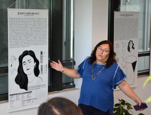 Núria Salán davant del panell de la Judit Giró a la visita guiada a l'Enciclopèdia de Dones STEAM a l'IMB-CNM