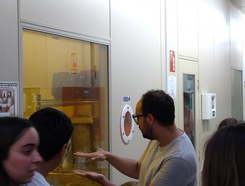 Luis Rull delante de Fotolitografía con público de la visita a la Sala Blanca de Micro y Nanofabricación